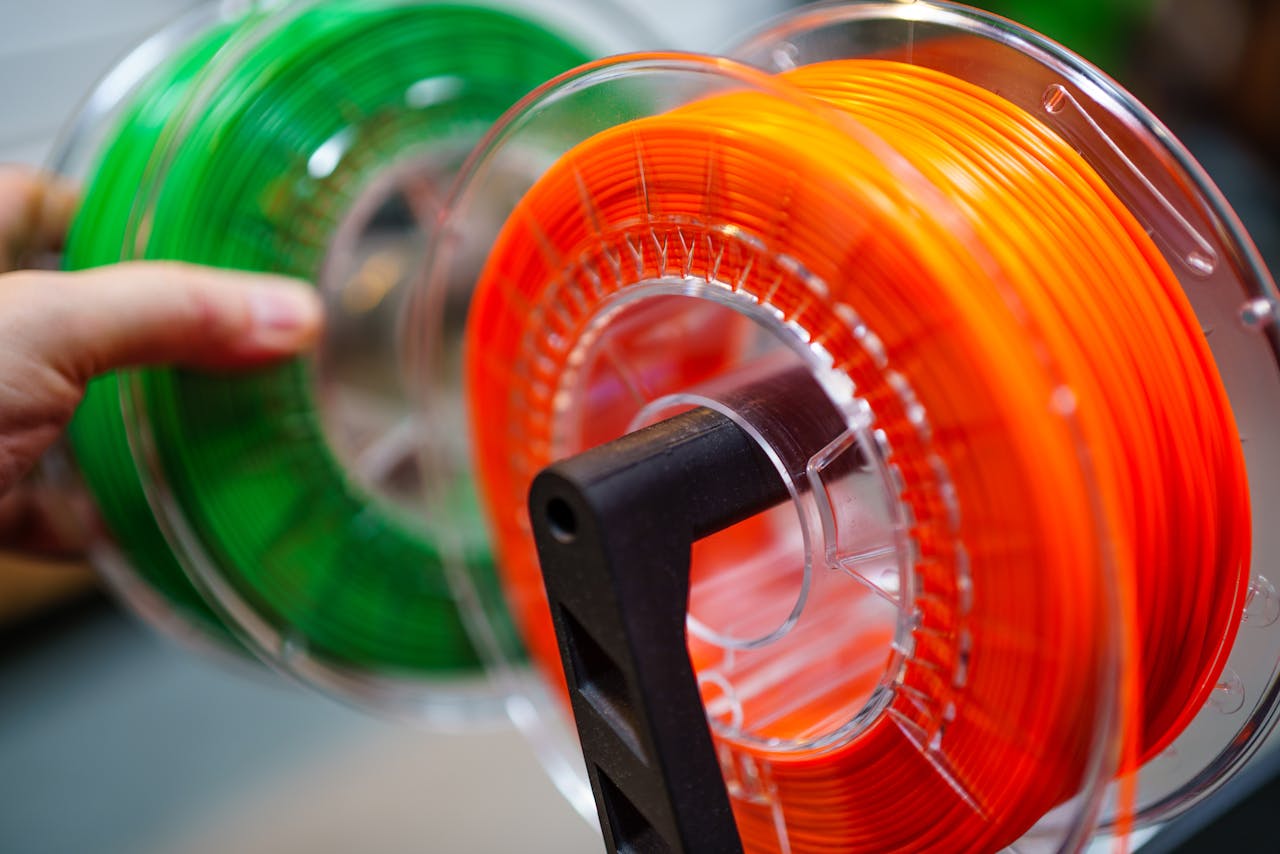services-img Vibrant orange and green 3D printer filament spools for innovative manufacturing uses.